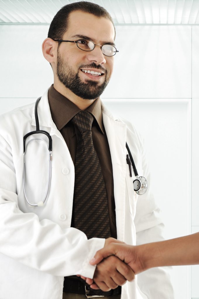 young adult doctor shaking hand of patient and smiling HtQX3A4i