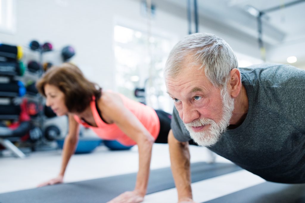 graphicstock beautiful fit senior couple in gym working out doing push ups S fyZzY8G